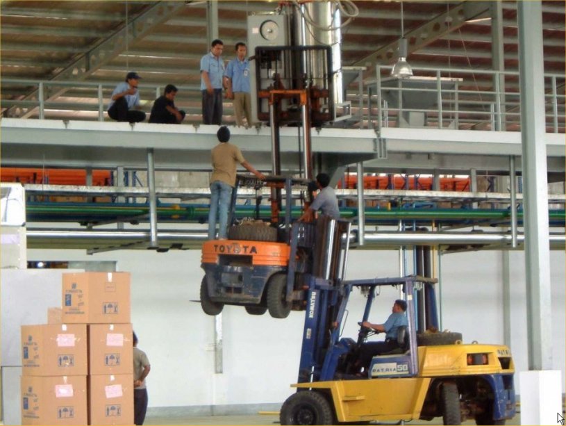 Closely supervised use of two forklifts to lift factory equipment to a raised mezzanine too high for one forklift to reach, what could possibly go wrong?
